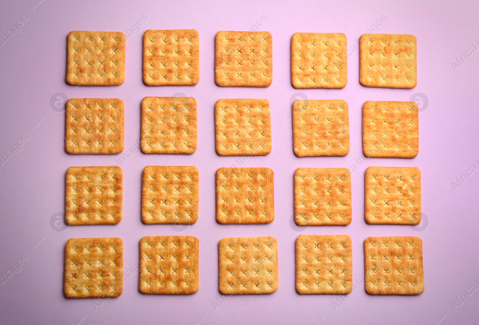Delicious crackers on violet background, flat lay Photo of Delicious crackers on violet background, flat lay