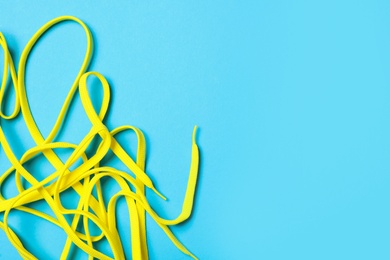 Yellow shoelaces on light blue background, flat lay. Space for text Photo of Yellow shoelaces on light blue background, flat lay. Space for text