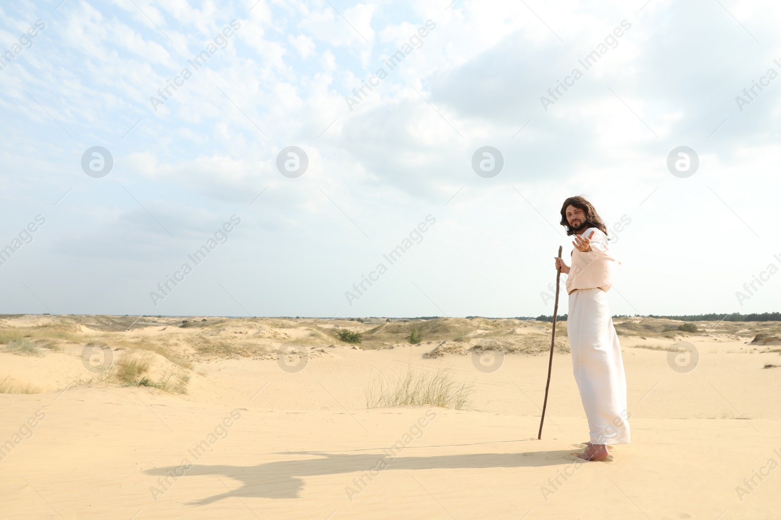 Jesus Christ walking with stick in desert. Space for text Photo of Jesus Christ walking with stick in desert. Space for text
