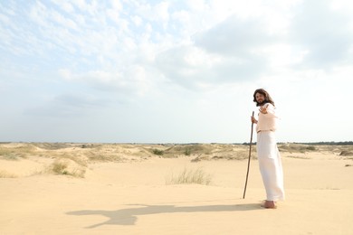 Jesus Christ walking with stick in desert. Space for text Photo of Jesus Christ walking with stick in desert. Space for text