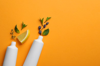 Blank tubes of toothpaste with herbs, lemon and lavender flowers on orange background, flat lay. Space for text Photo of Blank tubes of toothpaste with herbs, lemon and lavender flowers on orange background, flat lay. Space for text
