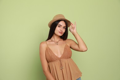 Beautiful young woman with straw hat on light green background Photo of Beautiful young woman with straw hat on light green background