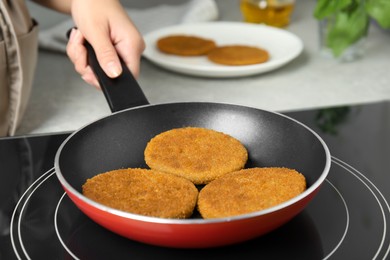 Woman cooking breaded cutlets in frying pan on stove, closeup Photo of Woman cooking breaded cutlets in frying pan on stove, closeup