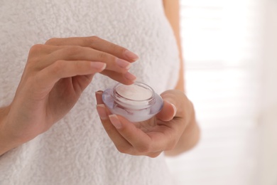 Woman holding jar with cream near window, closeup Photo of Woman holding jar with cream near window, closeup