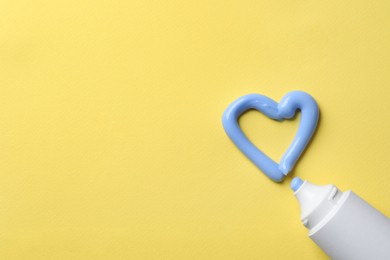 Blank tube and heart made with toothpaste on yellow background, flat lay. Space for text Photo of Blank tube and heart made with toothpaste on yellow background, flat lay. Space for text