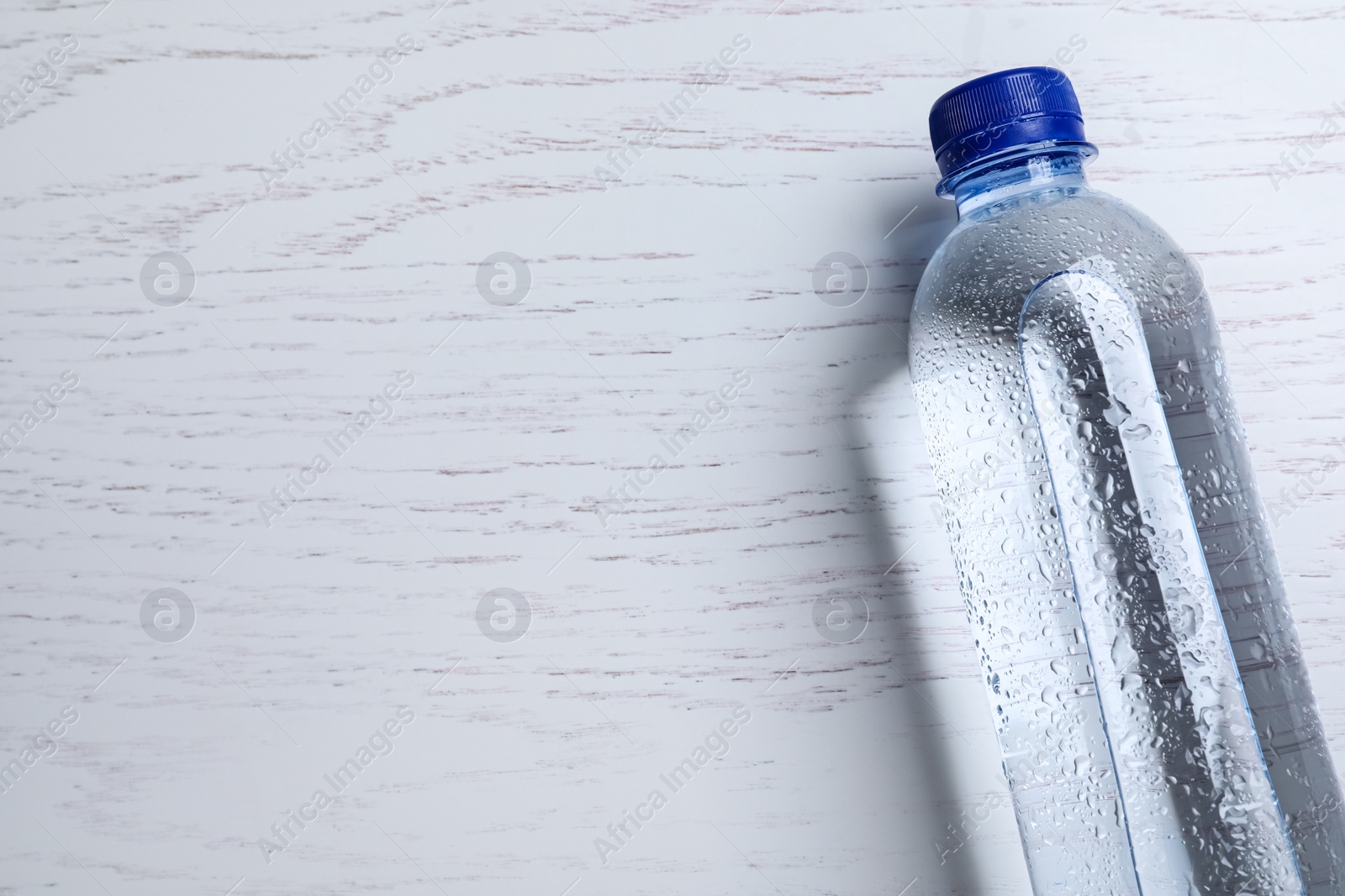 Plastic bottle with water on white wooden background, top view. Space for text Photo of Plastic bottle with water on white wooden background, top view. Space for text