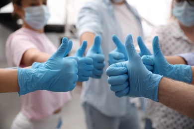 Group of people in blue medical gloves showing thumbs up on blurred background, closeup Photo of Group of people in blue medical gloves showing thumbs up on blurred background, closeup