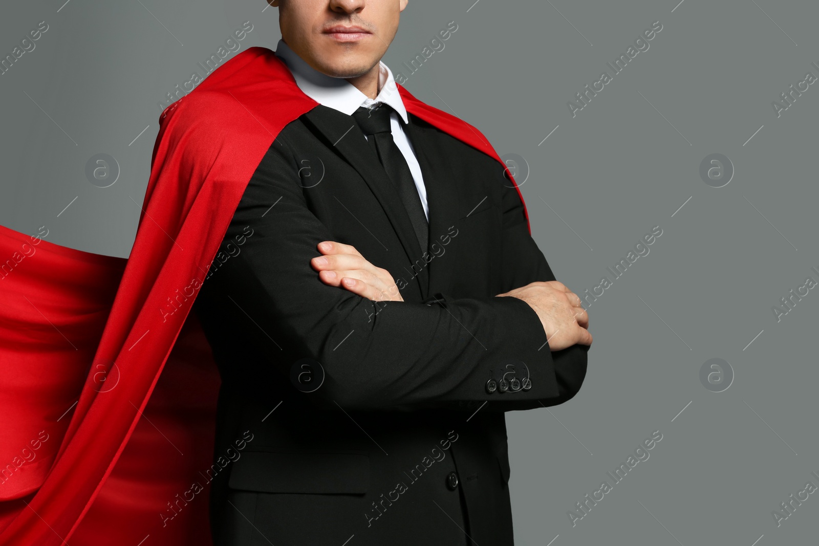 Businessman wearing superhero cape on grey background, closeup Photo of Businessman wearing superhero cape on grey background, closeup