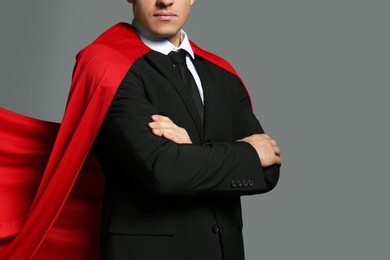 Businessman wearing superhero cape on grey background, closeup Photo of Businessman wearing superhero cape on grey background, closeup