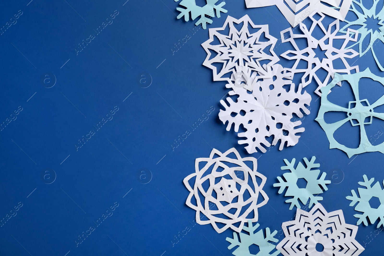 Many paper snowflakes on blue background, flat lay. Space for text Photo of Many paper snowflakes on blue background, flat lay. Space for text
