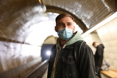 Young man in protective mask at subway station. Public transport Photo of Young man in protective mask at subway station. Public transport