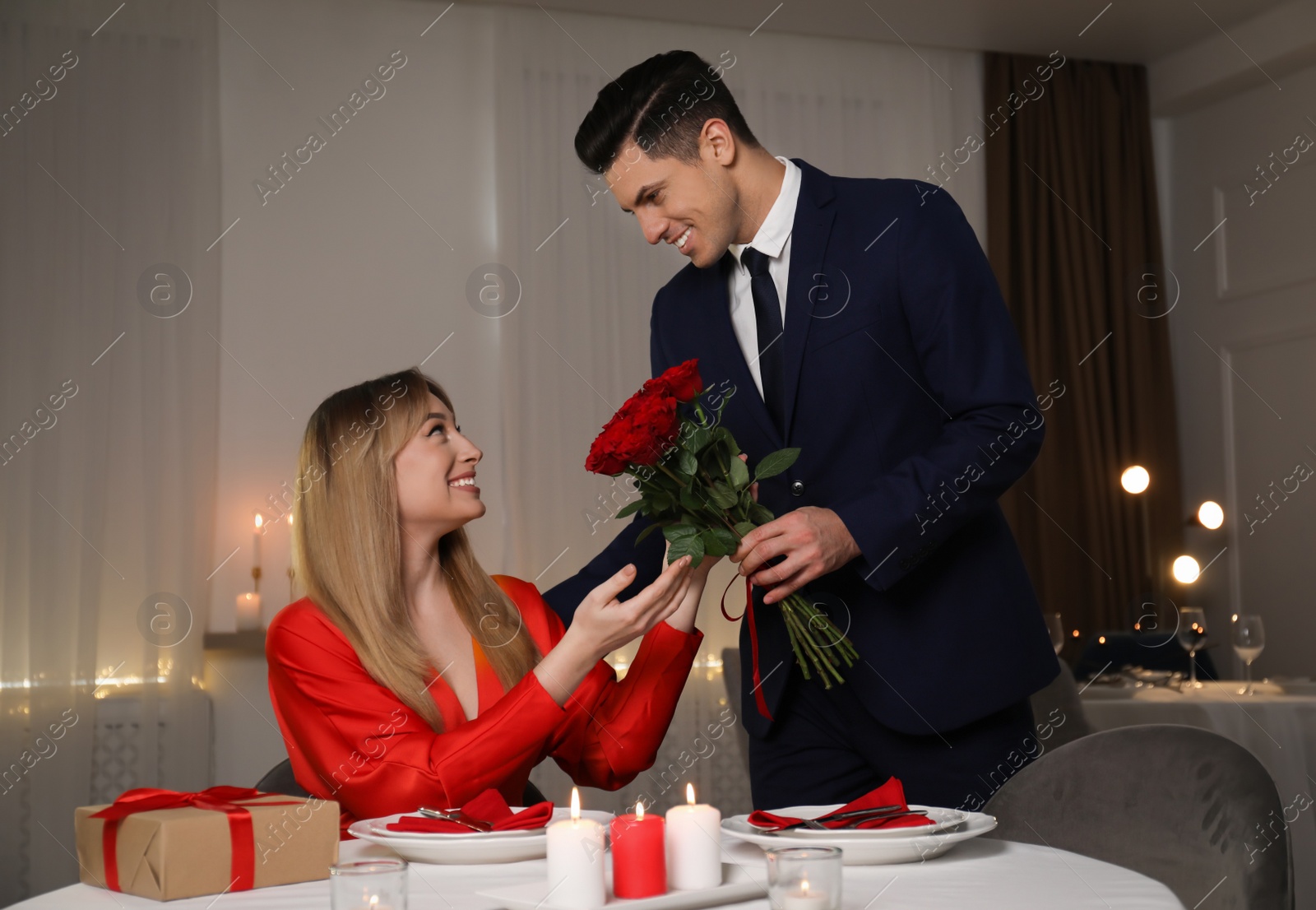 Man presenting roses to his beloved woman in restaurant at romantic dinner Photo of Man presenting roses to his beloved woman in restaurant at romantic dinner