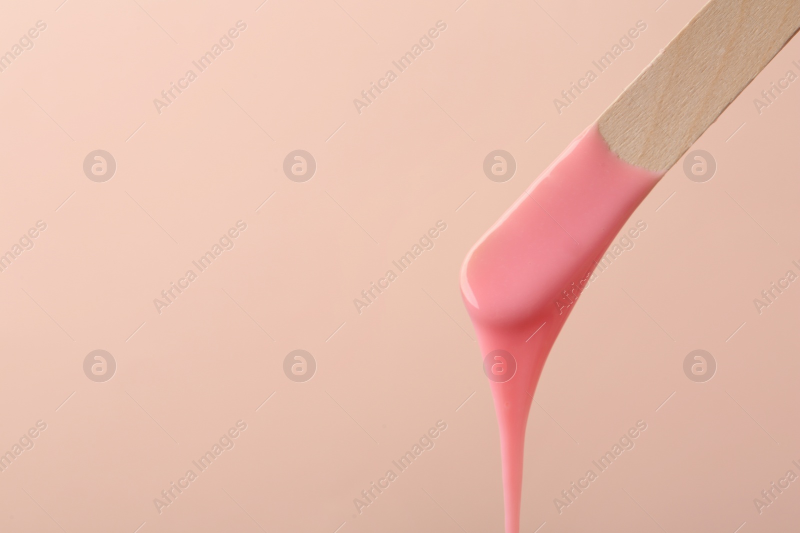 Wooden spatula with hot depilatory wax on beige background. Space for text Photo of Wooden spatula with hot depilatory wax on beige background. Space for text
