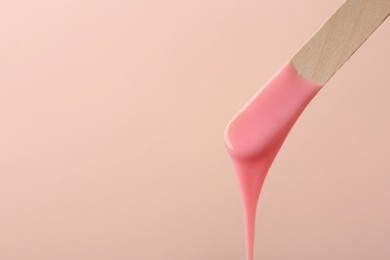 Wooden spatula with hot depilatory wax on beige background. Space for text Photo of Wooden spatula with hot depilatory wax on beige background. Space for text