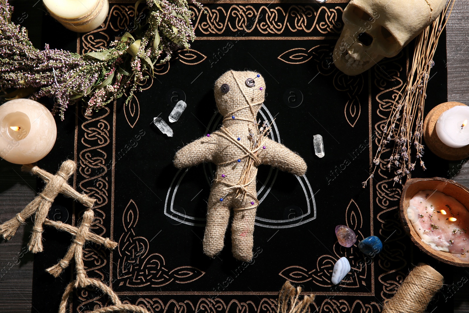 Voodoo doll pierced with pins surrounded by ceremonial items on table, flat lay. Curse ceremony Photo of Voodoo doll pierced with pins surrounded by ceremonial items on table, flat lay. Curse ceremony