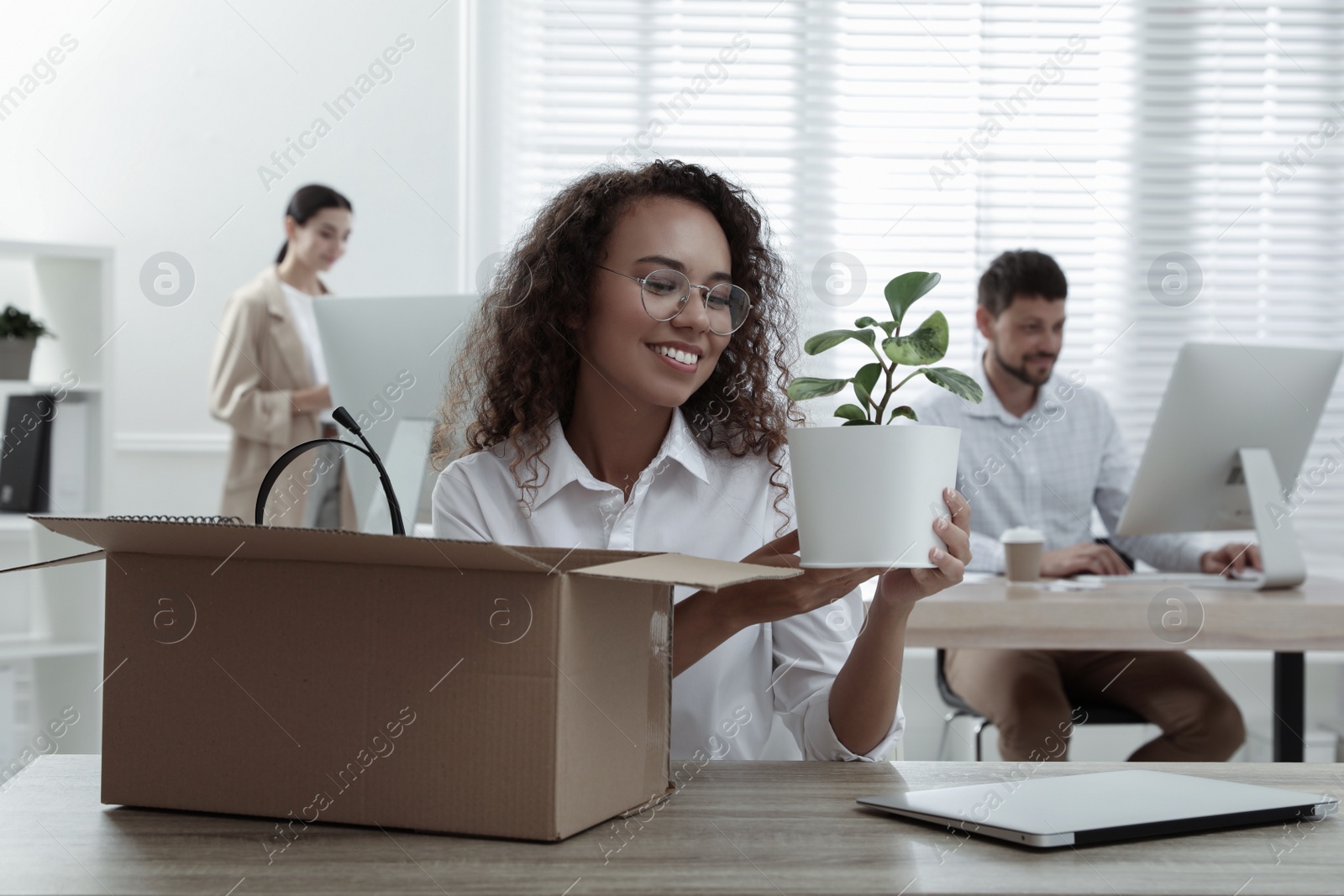 New coworker unpacking box with personal items at workplace in office Photo of New coworker unpacking box with personal items at workplace in office