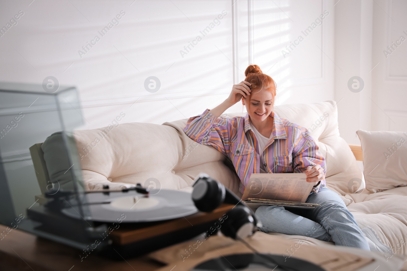 Young woman choosing vinyl disc to play music with turntable at home Photo of Young woman choosing vinyl disc to play music with turntable at home