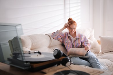 Young woman choosing vinyl disc to play music with turntable at home Photo of Young woman choosing vinyl disc to play music with turntable at home