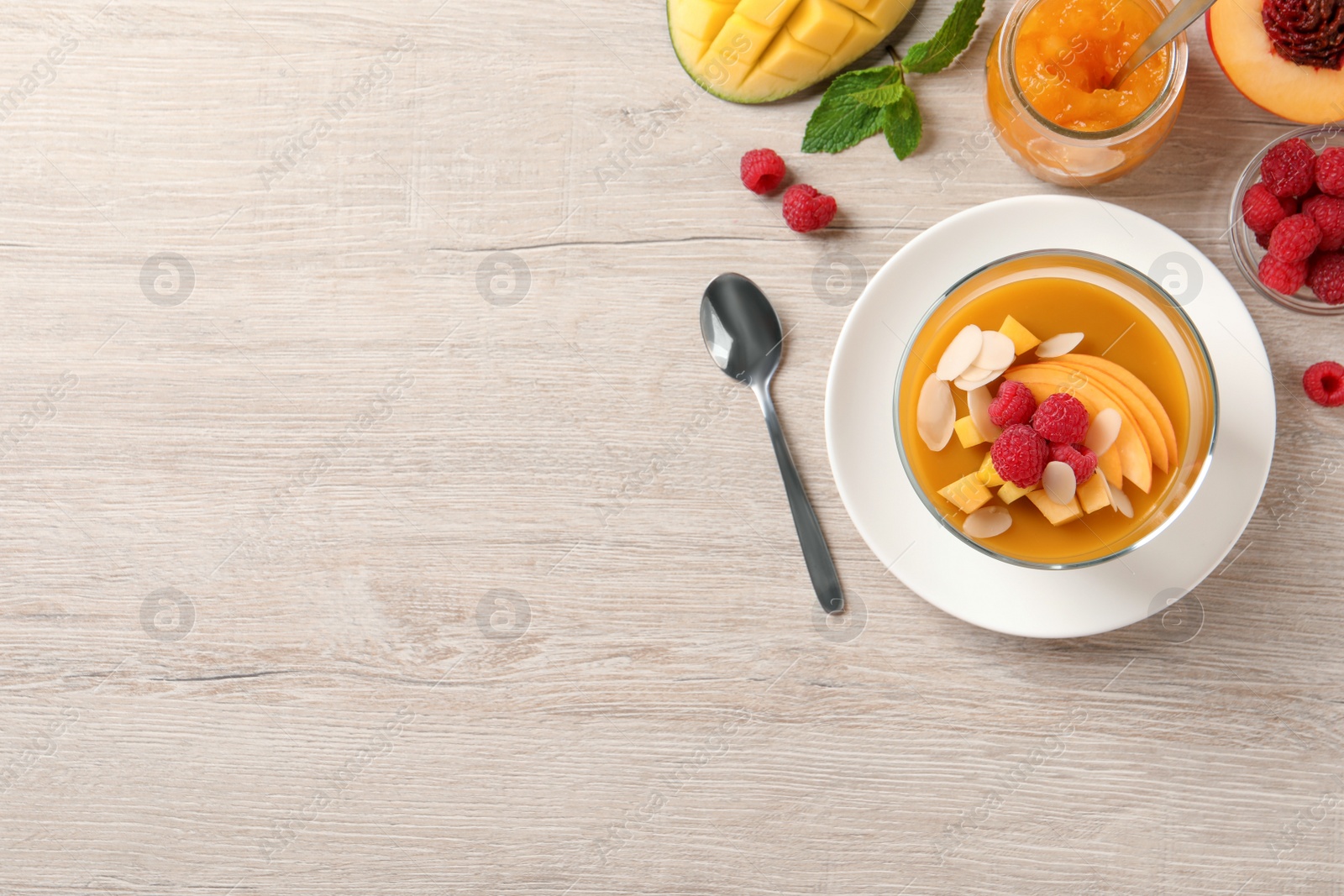 Delicious mango jelly with fresh raspberries and almond flakes on light wooden table, flat lay. Space for text Photo of Delicious mango jelly with fresh raspberries and almond flakes on light wooden table, flat lay. Space for text