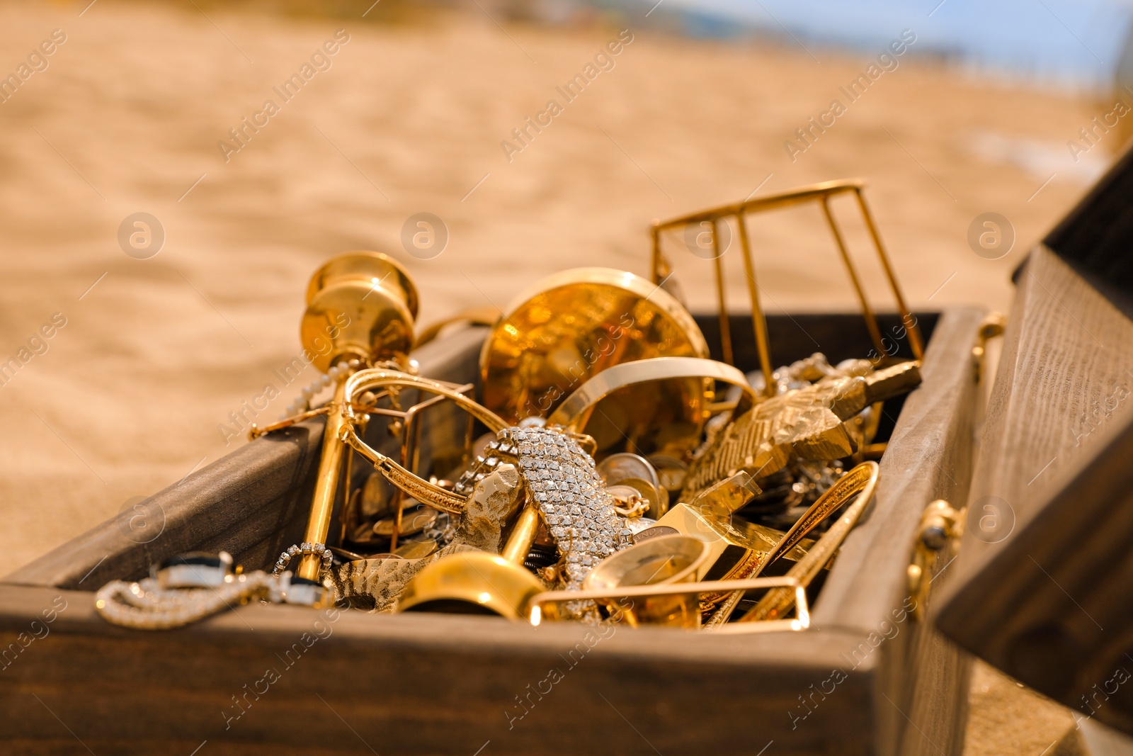 Open wooden treasure chest on sandy beach, closeup Photo of Open wooden treasure chest on sandy beach, closeup