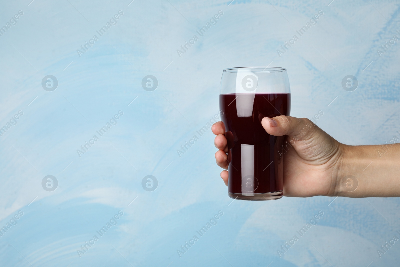 Woman with glass of juice on light blue, closeup. Space for text Image of Woman with glass of juice on light blue, closeup. Space for text