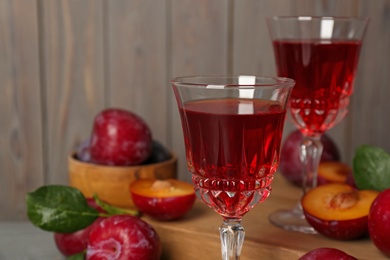 Delicious plum liquor on blurred background, closeup. Homemade strong alcoholic beverage Photo of Delicious plum liquor on blurred background, closeup. Homemade strong alcoholic beverage