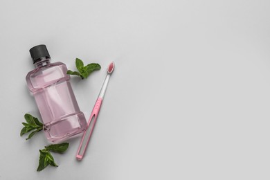 Photo of Mouthwash, toothbrush and mint on light grey background, flat lay. Space for text