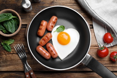 Romantic breakfast with fried sausages and heart shaped egg on wooden table, flat lay. Valentine's day celebration Photo of Romantic breakfast with fried sausages and heart shaped egg on wooden table, flat lay. Valentine's day celebration