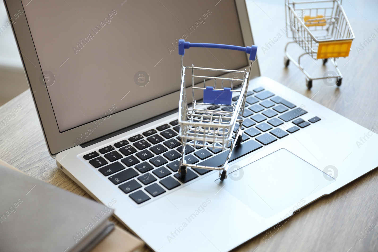 Internet shopping. Laptop and small carts on table, closeup Photo of Internet shopping. Laptop and small carts on table, closeup
