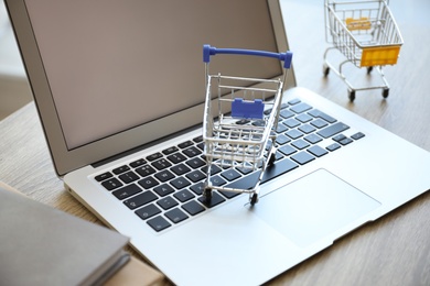 Internet shopping. Laptop and small carts on table, closeup Photo of Internet shopping. Laptop and small carts on table, closeup
