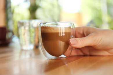 Photo of Woman with aromatic coffee at table in cafe, closeup