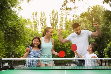Happy family playing ping pong in park Photo of Happy family playing ping pong in park