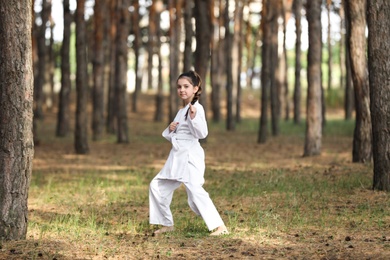 Cute little girl in kimono practicing karate in forest Photo of Cute little girl in kimono practicing karate in forest