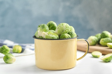 Metal mug with fresh Brussels sprouts on white table, closeup Photo of Metal mug with fresh Brussels sprouts on white table, closeup