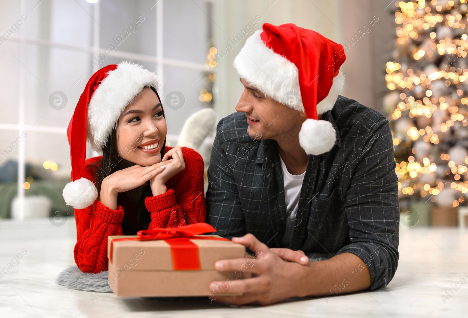 Man presenting Christmas gift to his girlfriend at home Photo of Man presenting Christmas gift to his girlfriend at home