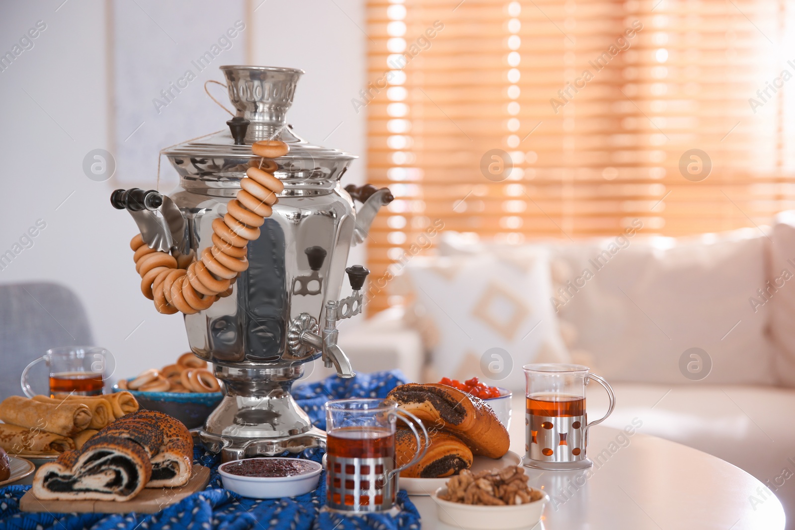 Traditional Russian samovar with treats on white table at home Photo of Traditional Russian samovar with treats on white table at home