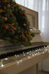 White piano with fairy lights and decorative wreath indoors, closeup. Christmas music Photo of White piano with fairy lights and decorative wreath indoors, closeup. Christmas music