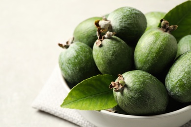 Delicious fresh feijoas in bowl on light grey table, closeup Photo of Delicious fresh feijoas in bowl on light grey table, closeup