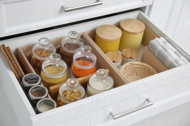 Open drawer with different jars indoors, closeup. Order in kitchen Photo of Open drawer with different jars indoors, closeup. Order in kitchen