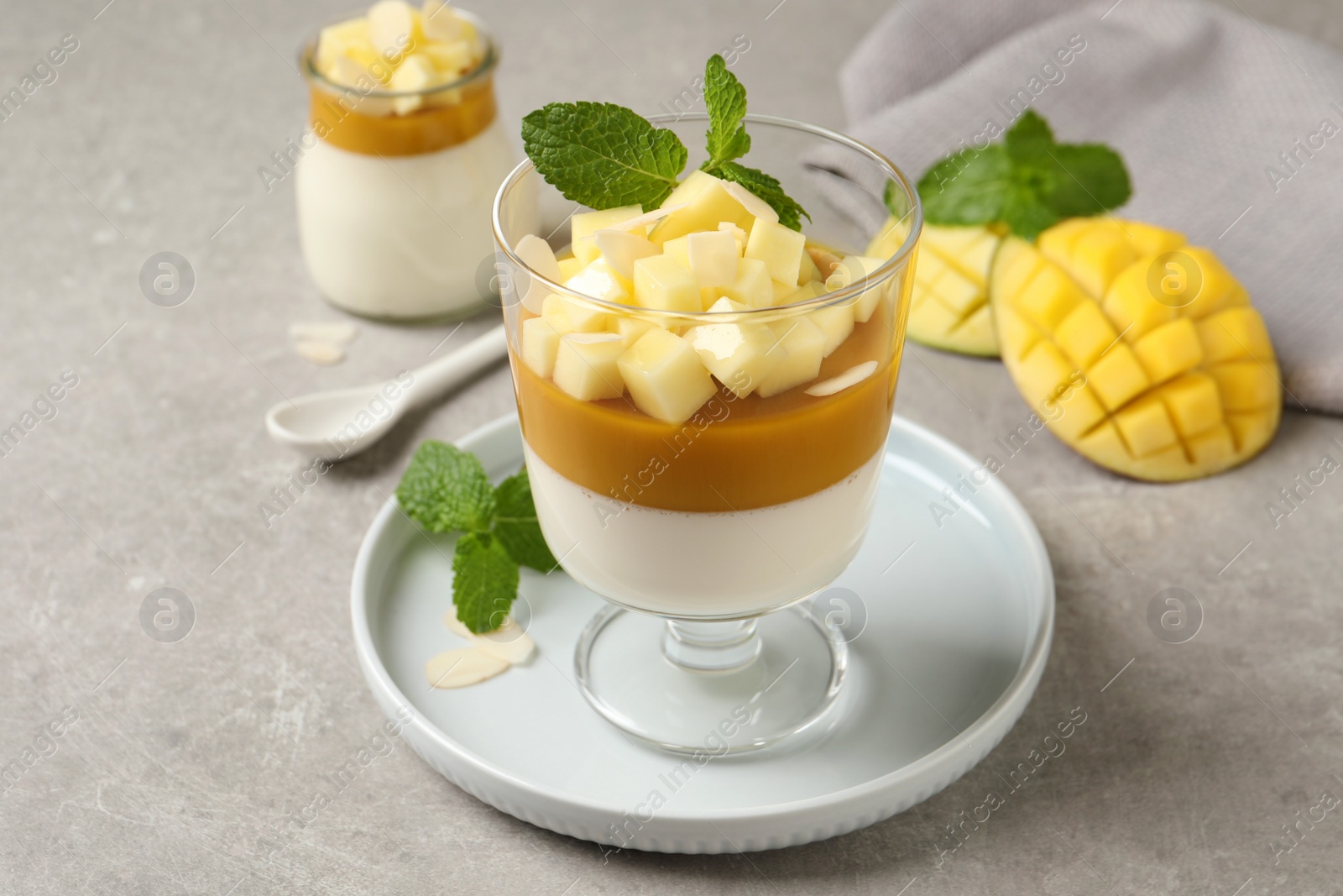 Delicious panna cotta with mango on grey table Photo of Delicious panna cotta with mango on grey table