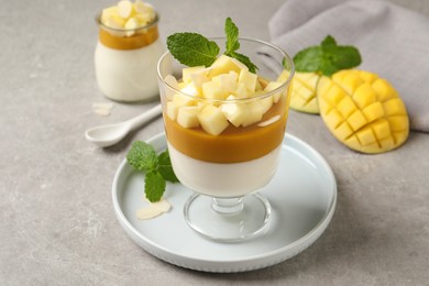 Delicious panna cotta with mango on grey table Photo of Delicious panna cotta with mango on grey table