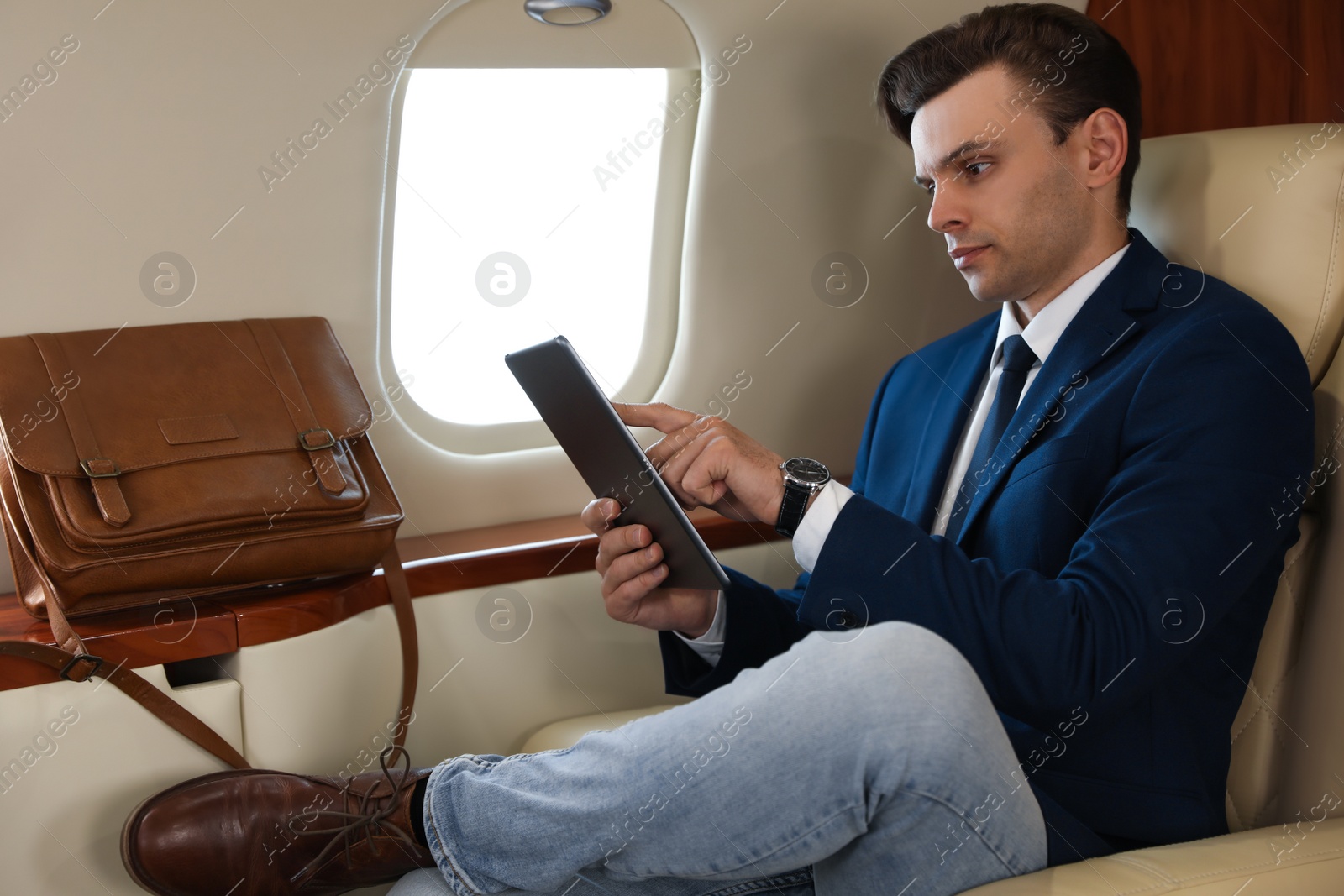 Businessman working on tablet in airplane during flight Photo of Businessman working on tablet in airplane during flight