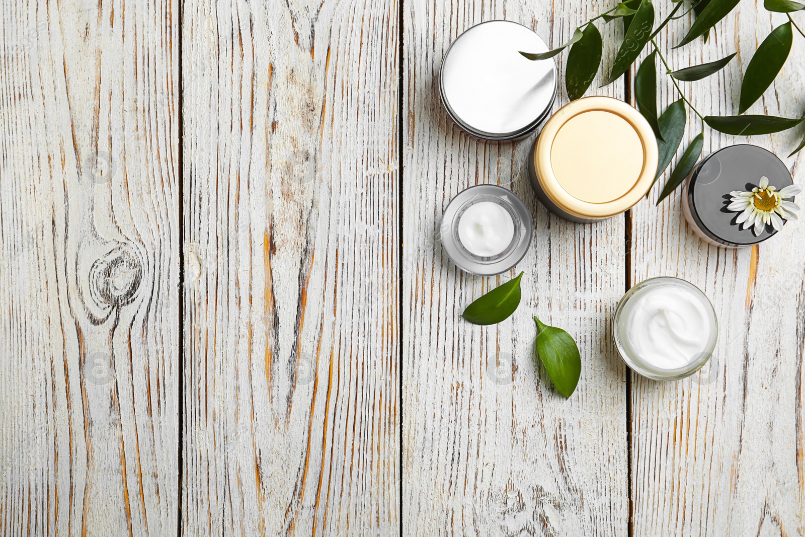 Composition with body cream in jars on wooden background, top view Photo of Composition with body cream in jars on wooden background, top view