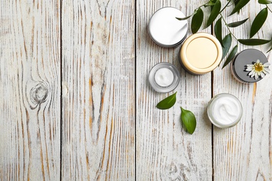 Composition with body cream in jars on wooden background, top view Photo of Composition with body cream in jars on wooden background, top view