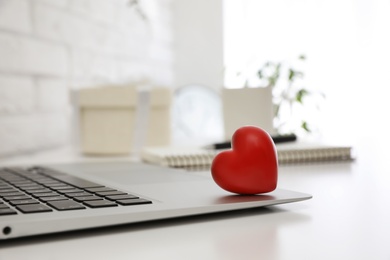 Red heart on laptop in office, space for text. Valentine's day celebration Photo of Red heart on laptop in office, space for text. Valentine's day celebration