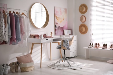 Dressing room interior with stylish makeup table, clothes and accessories Photo of Dressing room interior with stylish makeup table, clothes and accessories