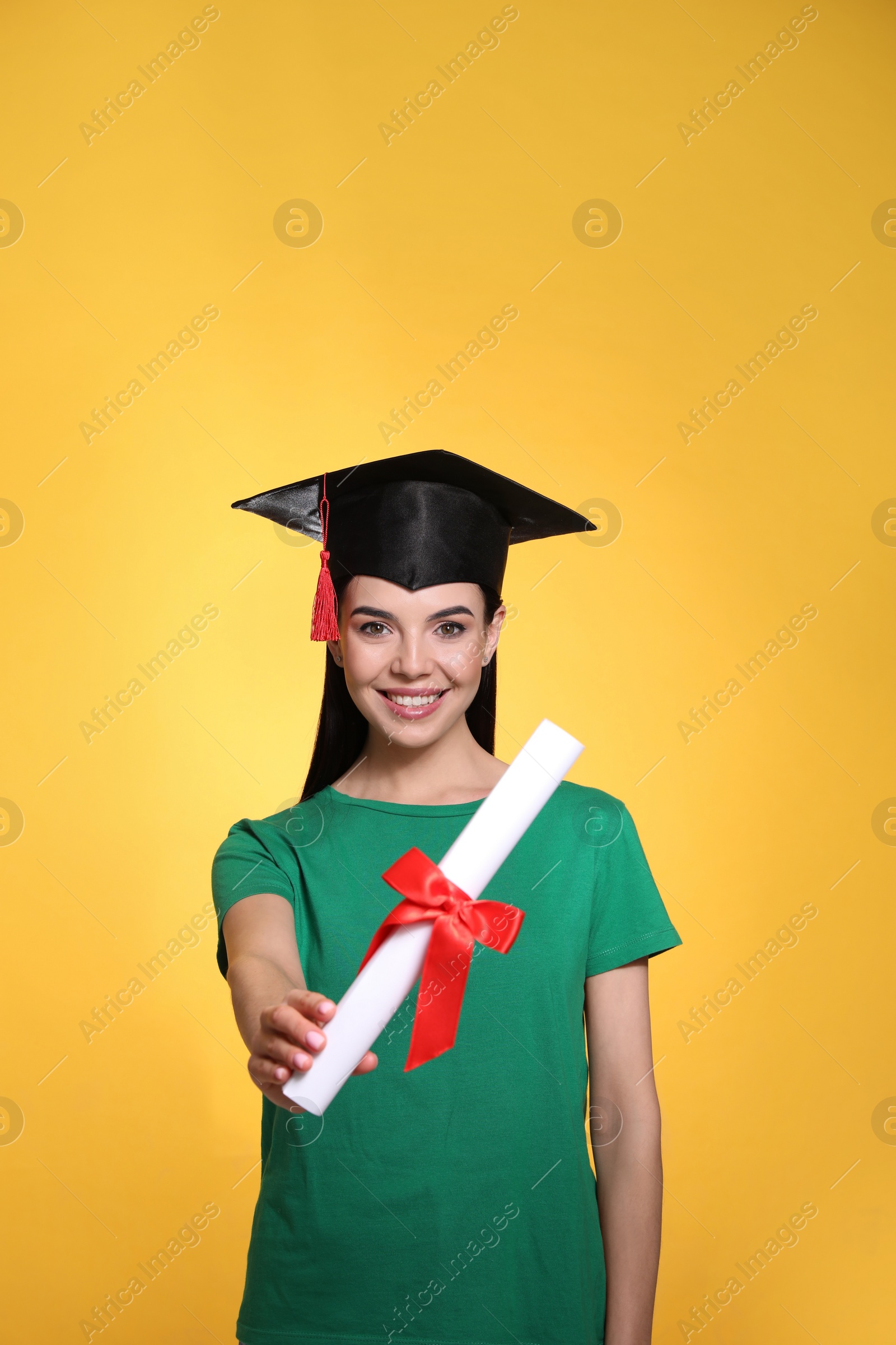 Happy student with graduation hat and diploma on yellow background Photo of Happy student with graduation hat and diploma on yellow background