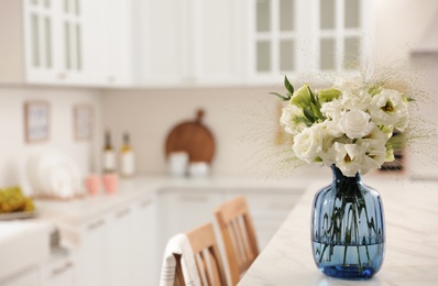 Bouquet of beautiful eustoma flowers on white table in kitchen. Interior design Photo of Bouquet of beautiful eustoma flowers on white table in kitchen. Interior design