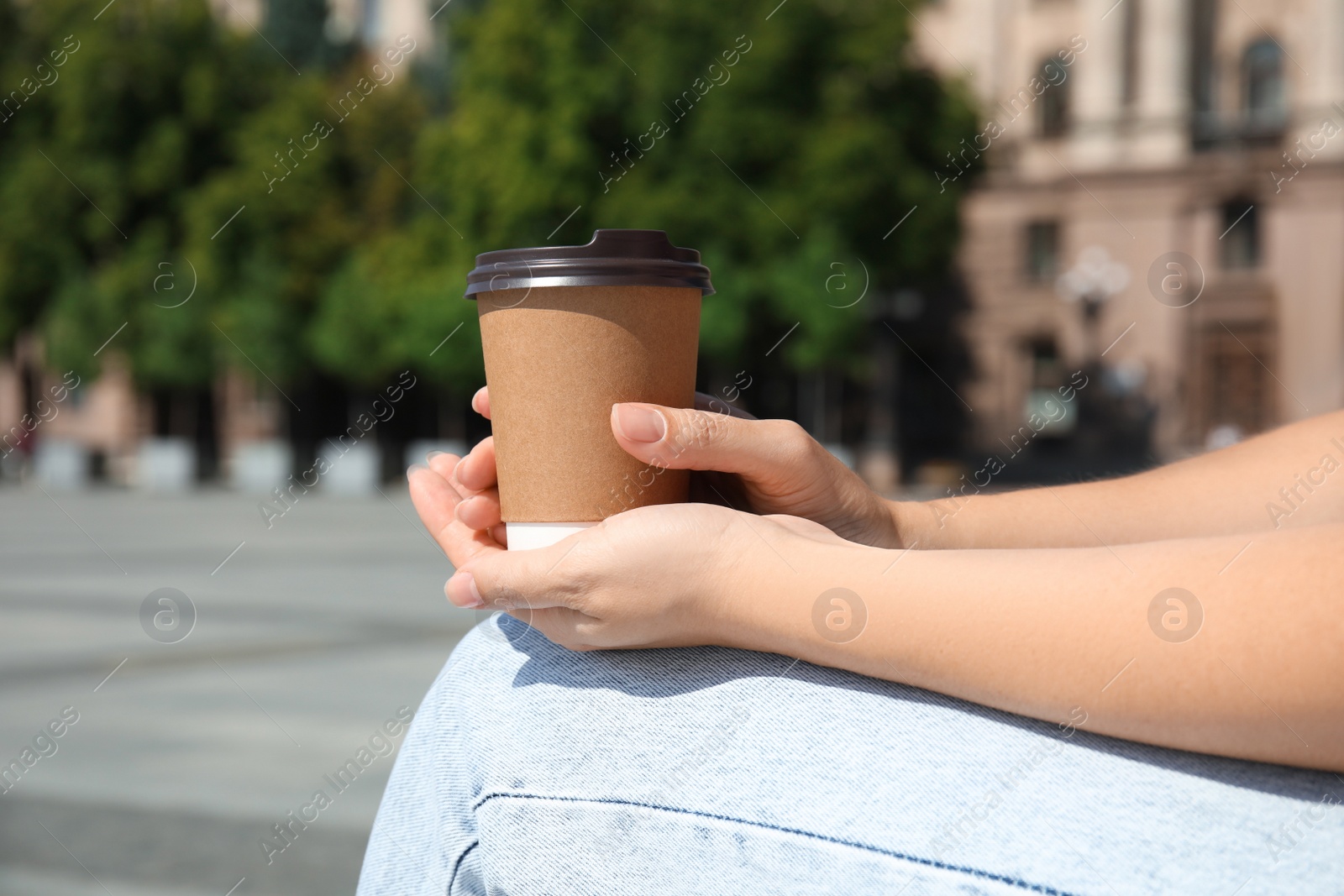 Woman holding takeaway cardboard coffee cup with plastic lid outdoors, closeup Photo of Woman holding takeaway cardboard coffee cup with plastic lid outdoors, closeup