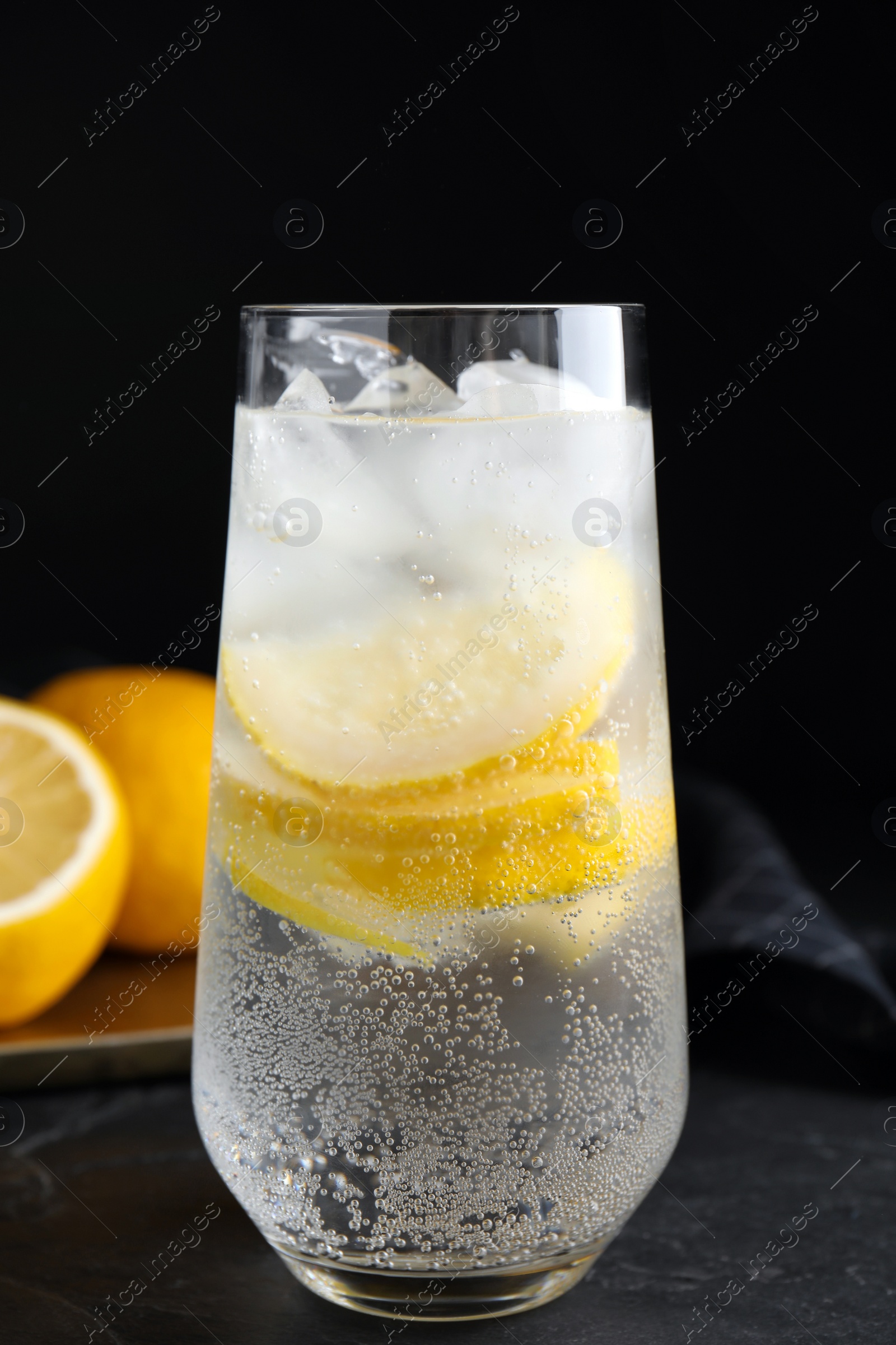 Soda water with lemon slices and ice cubes on black table Photo of Soda water with lemon slices and ice cubes on black table